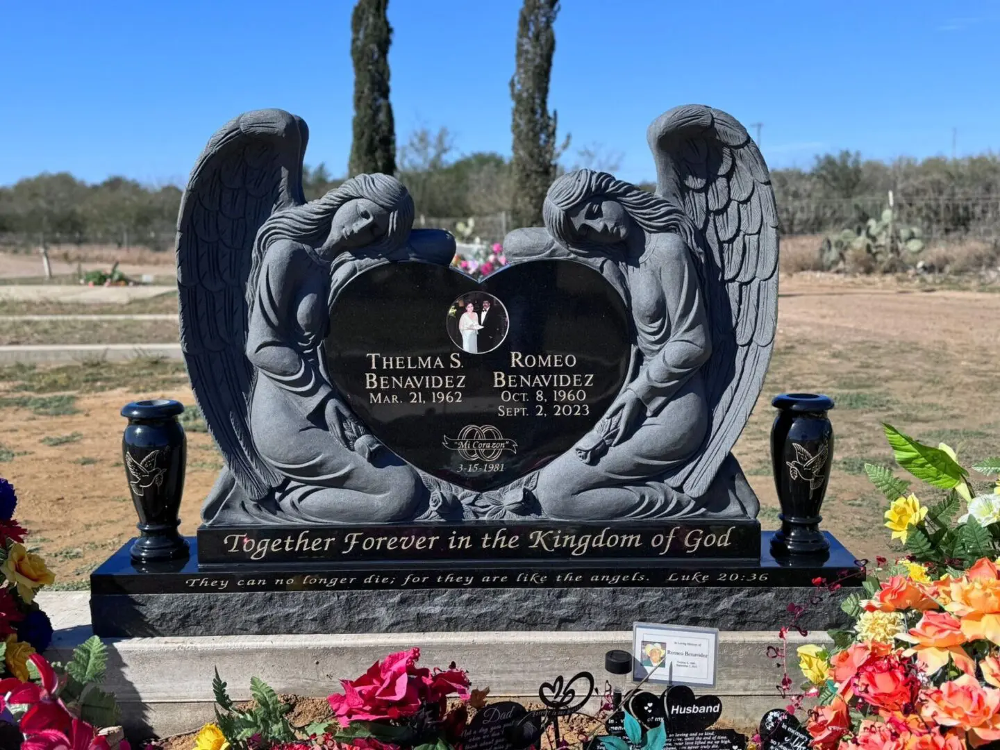 A grave with two angels and flowers in front of it.