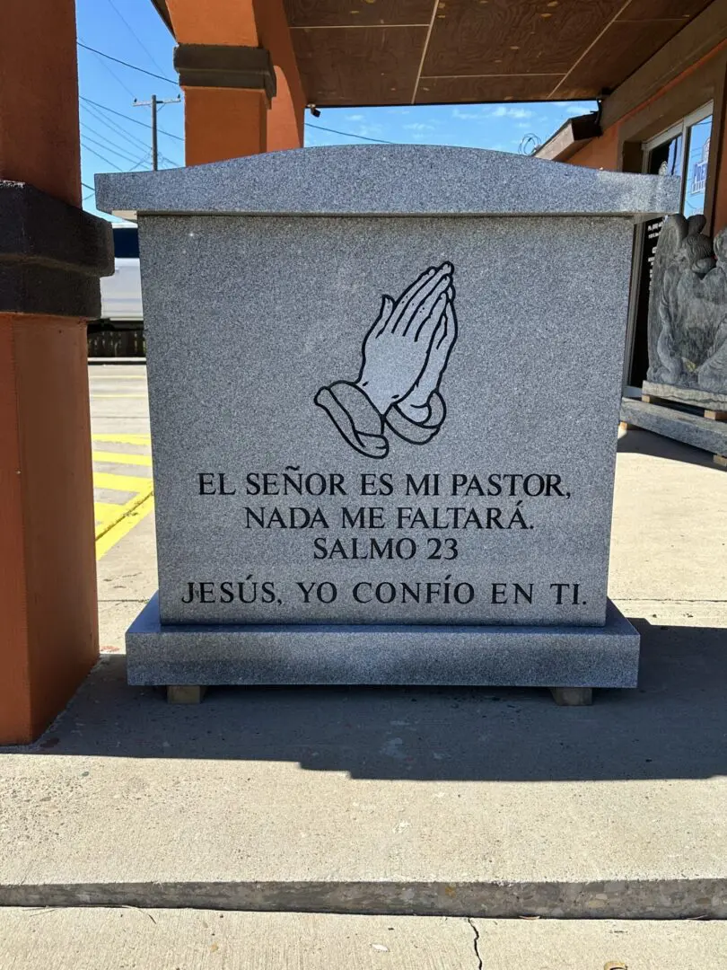 A stone tombstone with a picture of hands and text.